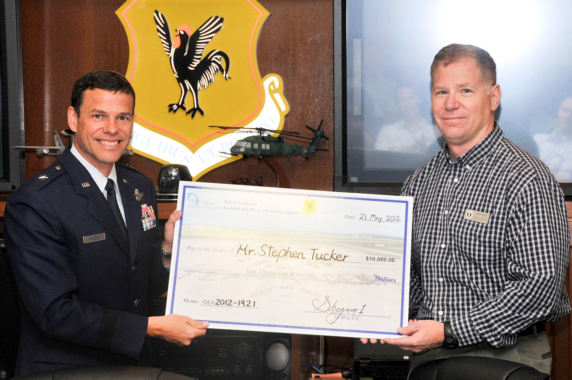 U.S. Air Force Brig. Gen. Matt Molloy, 18th Wing commander, presents a $10,000 check to Stephen Tucker, 18th Maintenance Group Air Force Engineering Technical Services lead and propulsion equipment specialist, during the Kadena team staff meeting on Kadena Air Base, Japan, May 21, 2012. Tucker, a retired chief master sergeant, received the check last month because of his submission to the IDEA program that saves the Air Force $89,000 per year in man hours and fuel costs. (U.S. Air Force photo/Staff Sgt. Darnell T. Cannady)