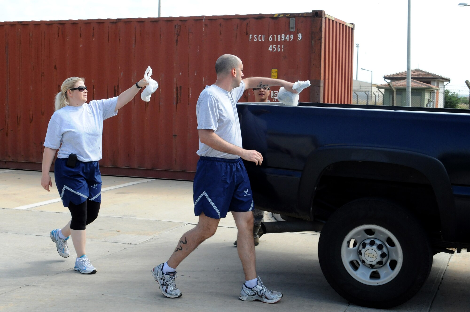 Airmen toss trash bags into the back of a truck following a foreign-object-debris walk on the flightline May 29, 2012, at Incirlik Air Base, Turkey.The FOD walk was a combined effort between the 39th Air Base Wing and Turkish air force 10th Tanker Base Command to clear the area of debris that could potentially damage aircraft engines. (U.S. Air Force photo by Senior Airman Marissa Tucker/Released)
