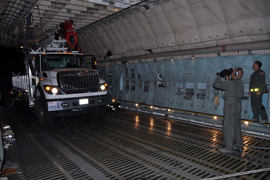 Reservists and technicians from March Air Reserve Base, Calif., answered the President's call to 'lean forward' with Hurricane Sandy relief efforts here Nov. 1, 2012, by loading Southern California Edison equipment onto a Travis Air Force Base C-5 Galaxy and a Joint Base Lewis-McChord C-17 Globemaster III. Here an Edison truck is marshalled into the cargo bay of a C-5. (U.S. Air Force photo/Linda Welz)