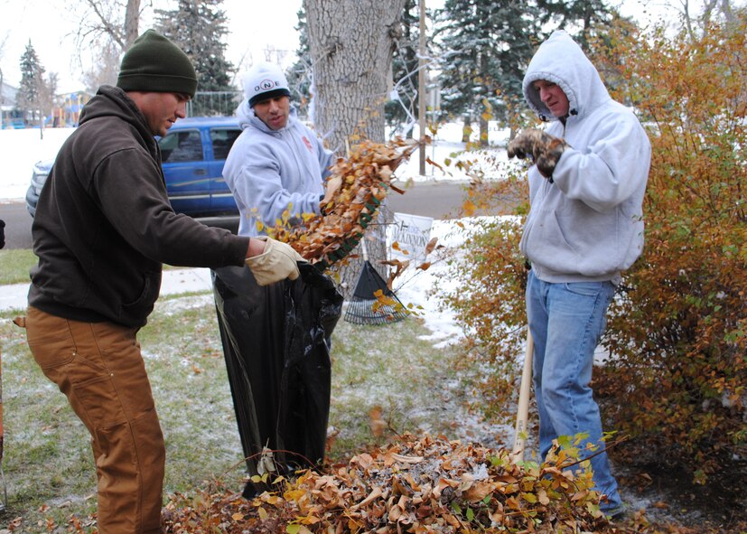 Tech. Sgt. Jason Hopper, 819th RED HORSE Squadron pavement and equipment operator, left, holds a garbage bag open as Tech. Sgt. Henry Ayala, center, and Senior Airman Corey Weaver, both 819th RHS pavement and equipment operators, take turns putting leaves in it.  During the Day of Caring volunteers did various jobs around the houses of community members in need, including raking leaves and light housework.  (U.S. Air Force photo/Airman 1st Class Cortney Paxton)
