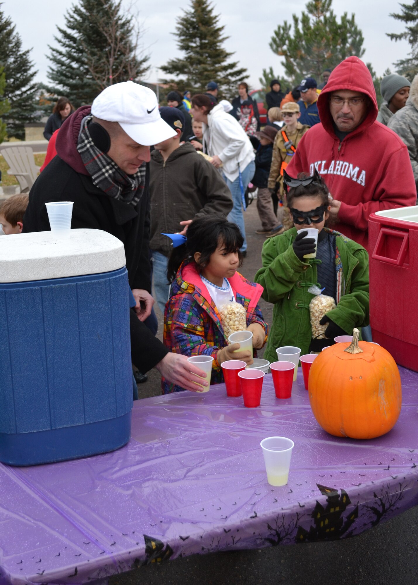 Col. Bruce Roehm, 341st Medical Group commander, far left, fills cups with lemonade as Senior Master Sgt. Kraig Nadjkovic, 819th RED HORSE Squadron first sergeant, and his daughters Aiden, 8 (right), and Kendall, 6, take one.  Most leaders of Wing One were in attendance to help families celebrate Halloween.  (U.S. Air Force photo/Airman 1st Class Cortney Paxton)
