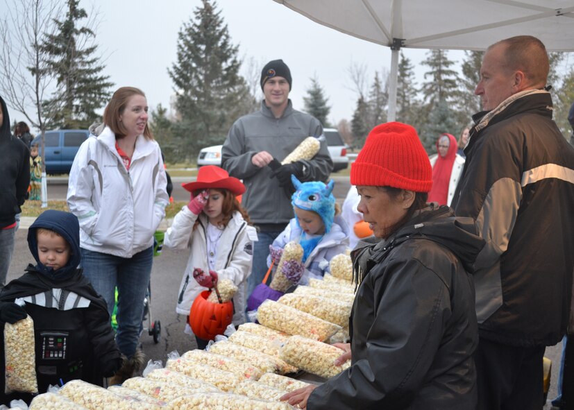 Col. David Lynch, 341st Security Forces Group commander, far right, and his wife Leah hand out popcorn to the families attending the wing commander and command chief’s Halloween party.  (U.S. Air Force photo/Airman 1st Class Cortney Paxton)