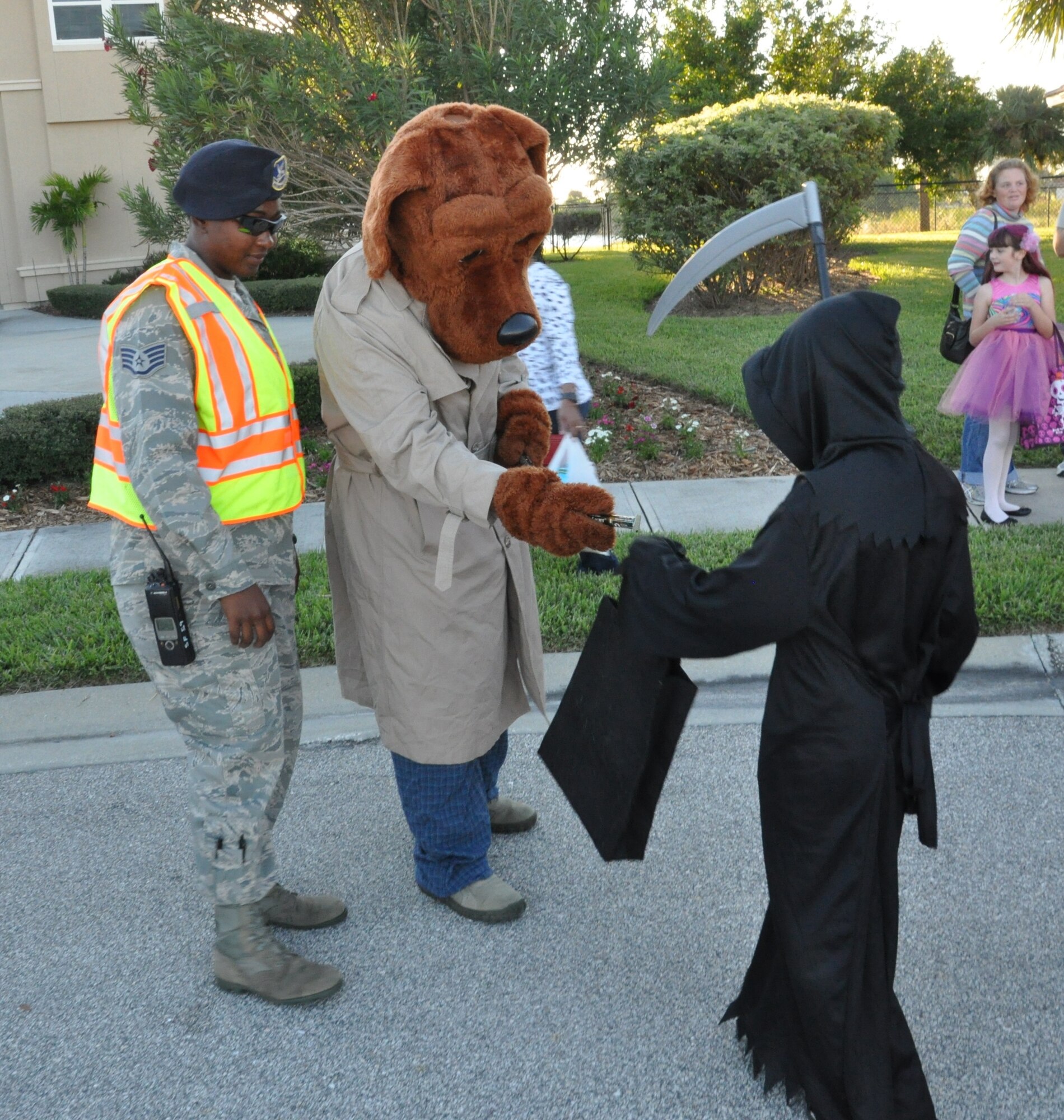Pumpkin Patrol personnel and McGruff the Crime Dog hand out glow sticks to children in the base community.  