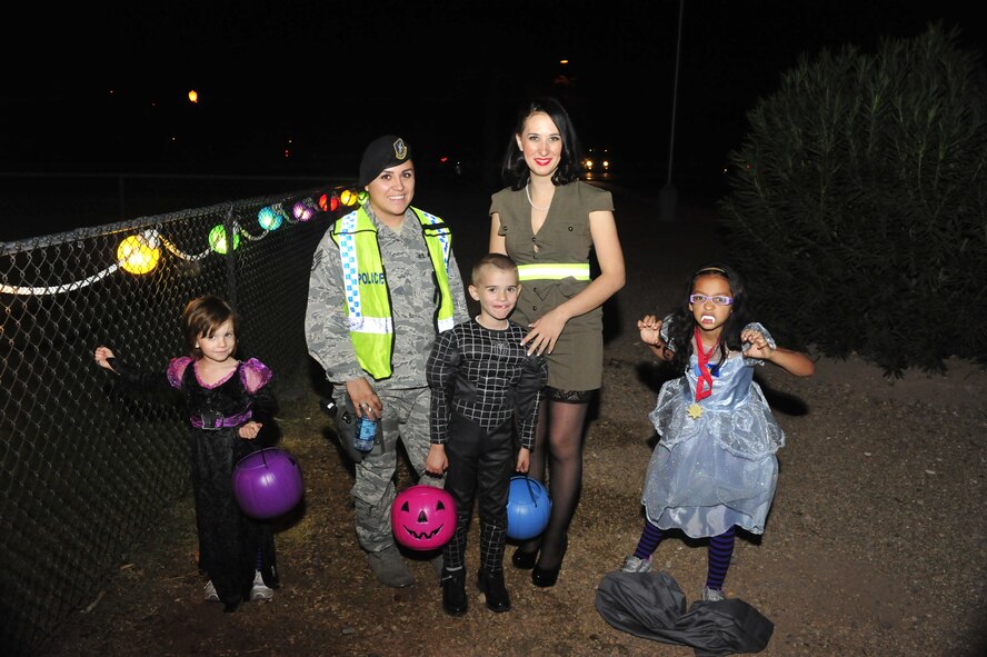 Staff Sgt. Arlene Gutierrez, 56th Security Forces Squadron patrolman, poses for a photo with a family of trick or treaters at Luke Air Force Base, Ariz., Oct. 31, 2012. The 56th SFS and volunteers from Luke performed "Pumpkin Patrol," to help provide a safe Halloween night experience. (U.S. Air Force photo by Staff Sgt. Jason Colbert)