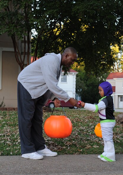 Chief Master Sgt. Freddie Flowers, 2nd Civil Engineer Squadron superintendent, gives candy to Tahj Shepherd, son of Tech. Sgt. Darius Shepherd, 2nd Maintenance Squadron Aerospace Ground Equipment flight, during trick-or-treating on Barksdale Air Force Base, La., Oct. 31. From 5:30 p.m. to 8:00 p.m. the base housing areas was open to Barksdale Airmen and their families for trick-or-treating. (U.S. Air Force photo/Airman 1st Class Benjamin Gonsier)(RELEASED)