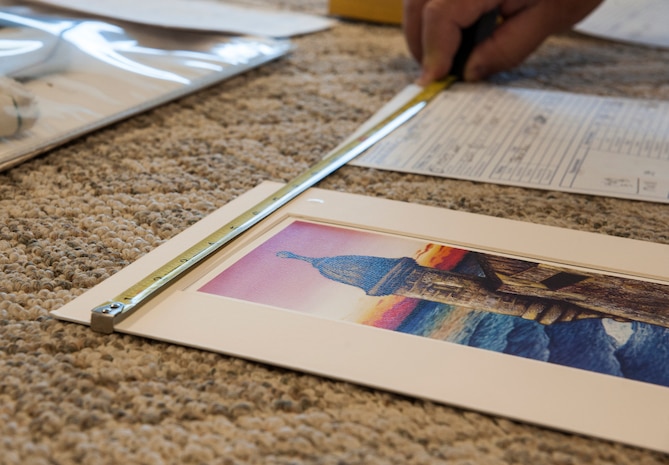 Kevin Parent, 628th Force Support Squadron master framer, measures the dimensions for a mat to a painting Oct. 29, 2012 at Joint Base Charleston - Air Base, S.C. A computerized mat cutter enables the framer to include three-dimensional bevels, offset corners, ovals, circles, ribbons, shapes and designs. (U.S. Air Force photo/Airman 1st Class Ashlee Galloway)