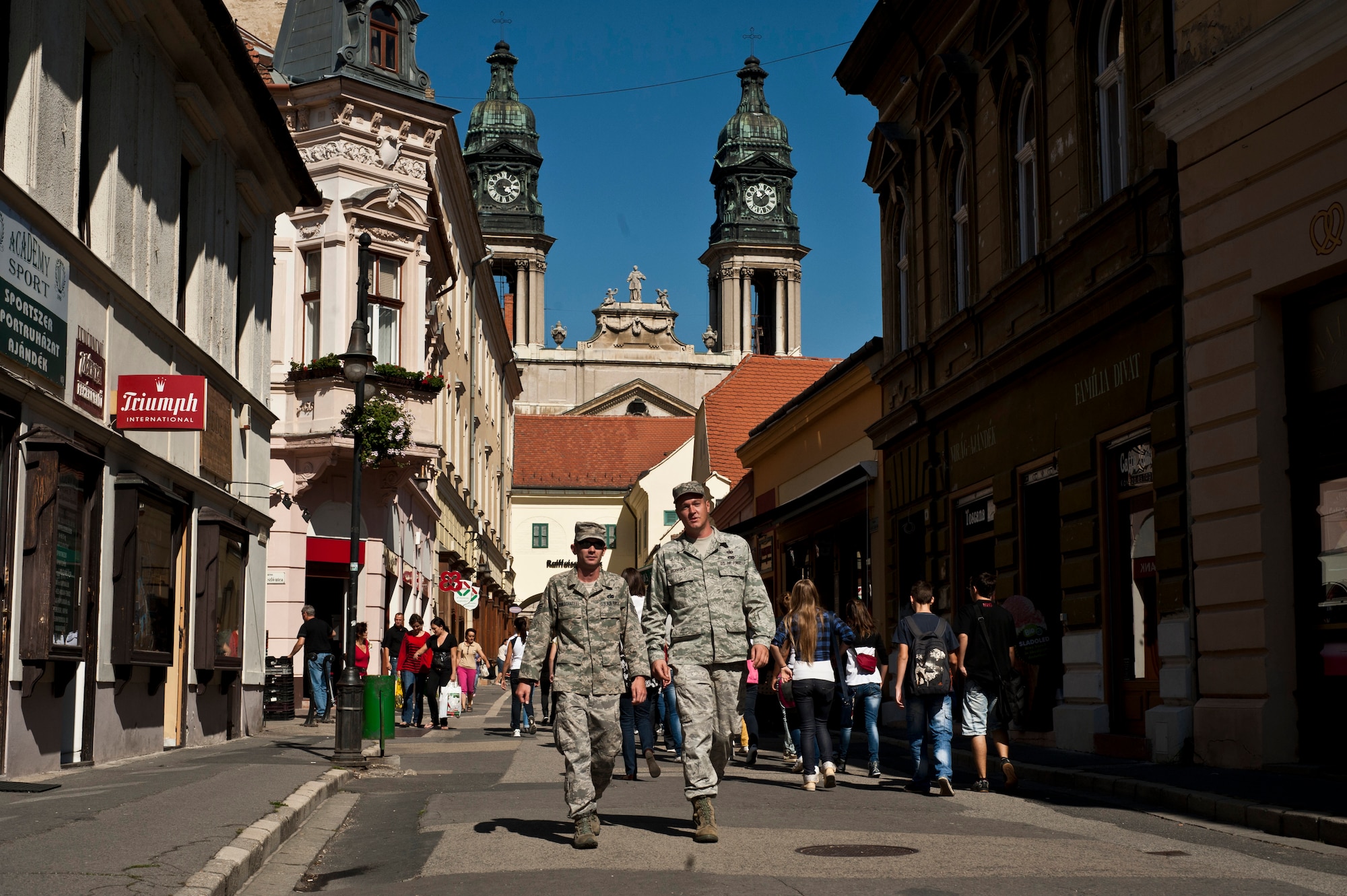 Staff Sgt. Justin Van Scheffel and Tech. Sgt. Brian Robisky walk to lunch through the "walking street" in downtown Papa, Hungary. U.S. Airmen have become a common sight in Papa since the air base was selected to host the operational arm of the Strategic Airlift Capability. The initial cadre of the Heavy Airlift Wing arrived to Papa in October 2008. (U.S. Air Force photo/Tech. Sgt. Bennie J. Davis III)