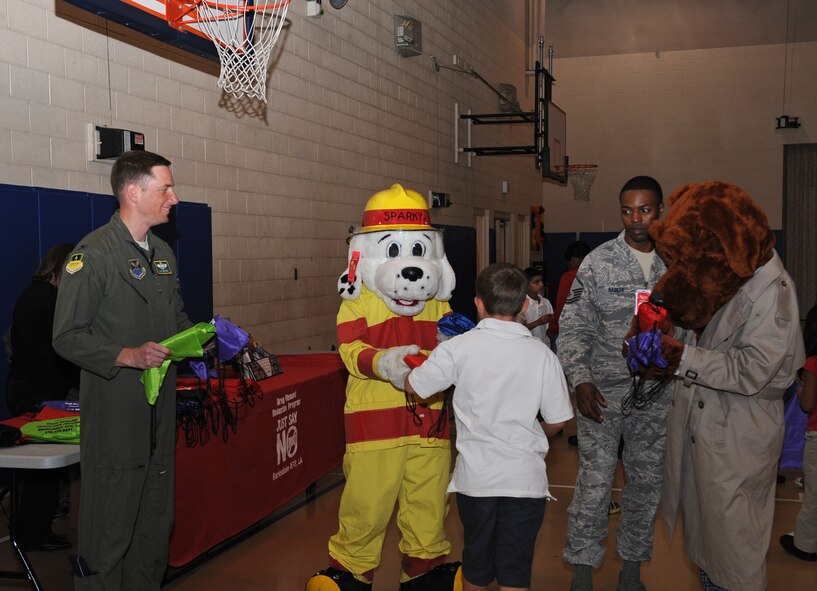 Col. Alexis Mezynski, 2nd Bomb Wing vice commander, Sparky the Fire Dog and McGruff the Crime Dog hand out goodie bags to all attendees during Red Ribbon Week on Barksdale Air Force Base, La., Oct. 30. Red Ribbon Week is dedicated to inform the community on the dangers of drug and alcohol abuse. More than 80 children pledged to be drug-free. (U.S. Air Force photo/Airman 1st Class Benjamin Gonsier)(RELEASED)
