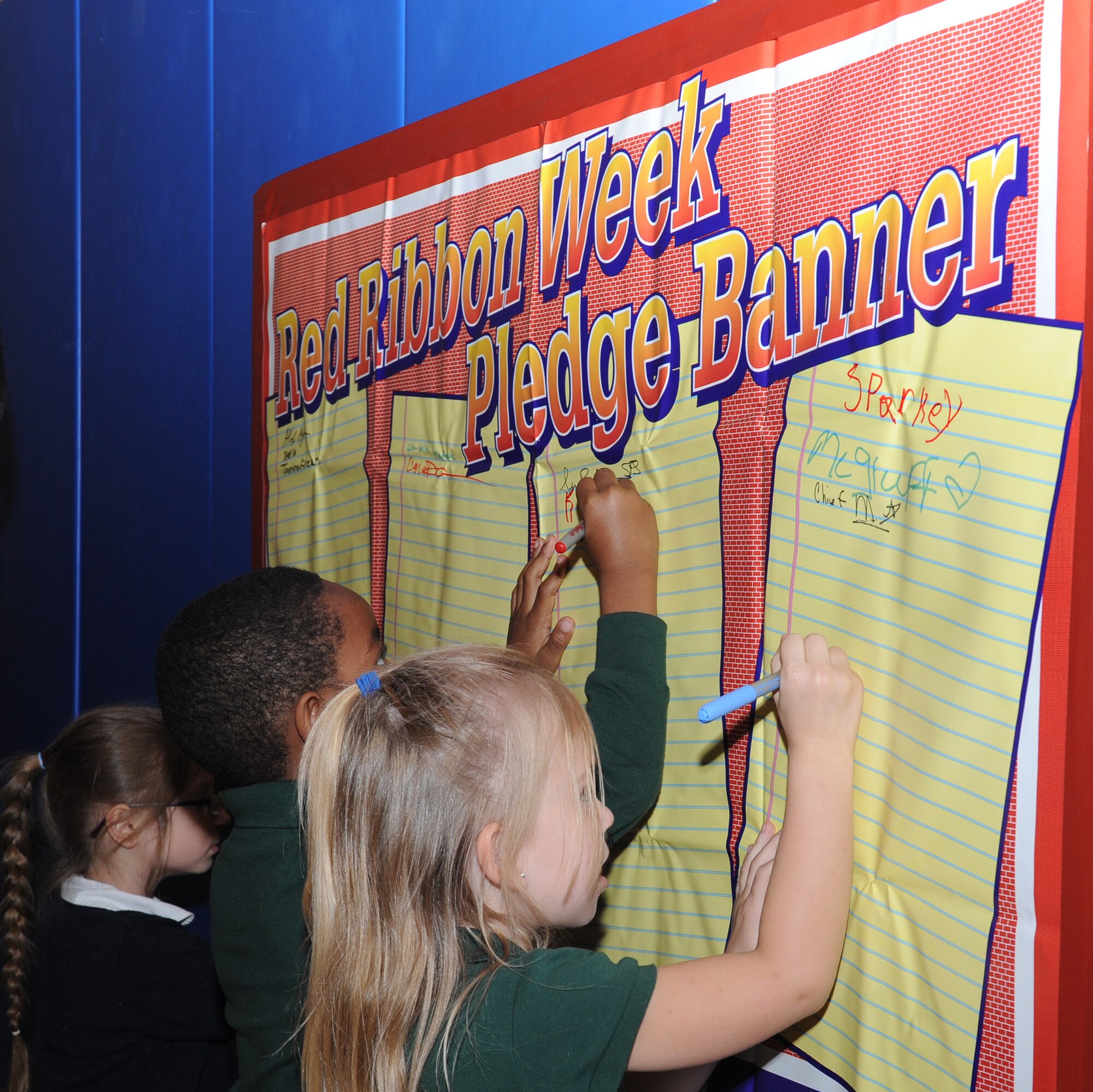 Children attending the youth center sign a banner pledging to be drug-free during Red Ribbon Week on Barksdale Air Force Base, La., Oct. 30. Red Ribbon Week is dedicated to inform the community on the dangers of drug and alcohol abuse. It is celebrated annually from Oct. 23-31. (U.S. Air Force photo/Airman 1st Class Benjamin Gonsier)(RELEASED)
