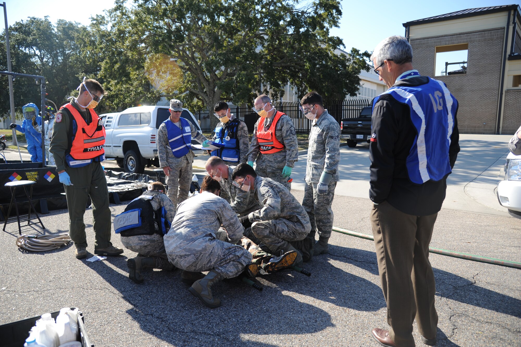 Jim Horton, Air Education and Training Command deputy inspector general, evaluates as members of the 81st Medical Group administers medical treatment on an injured “victim” during a hazardous material and major accident response exercise Oct. 31, 2012, at Hangar 4, Keesler Air Force Base, Miss.  The exercise scenario consisted of a group of Airmen cleaning inside the hangar in preparation for demolition when a shelf holding old munitions fell to the ground causing one to break open, explode and splash an “oily substance” on several of the “victims.”  The exercise helped prepare first responders in the event of a real-world incident.  (U.S. Air Force photo by Kemberly Groue)