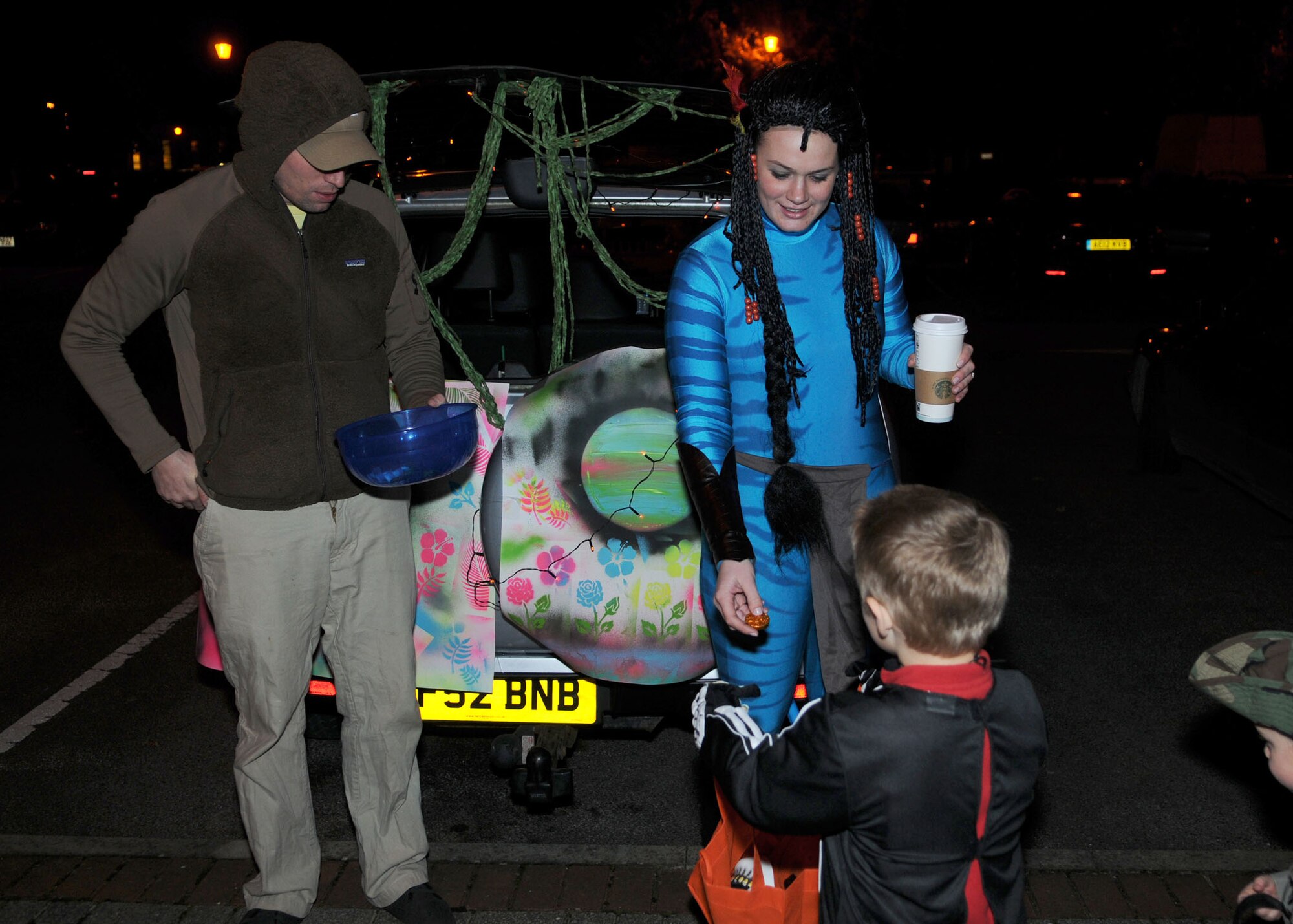 Staff Sgt. Amanda McDowell, 100th Communications Squadron client systems team assistant NCO in charge, and her husband Ryan pass out candy at the Trunk-or-Treat Spooktacular Oct. 31, 2012, at RAF Mildenhall, England.  At the event, decorative, candy-filled vehicles lined the sidewalk in front of the Galaxy Club giving children a safe place to collect candy on Halloween.  (U.S. Air Force photo by Staff Sgt. Tabitha M. Lee/Released)
