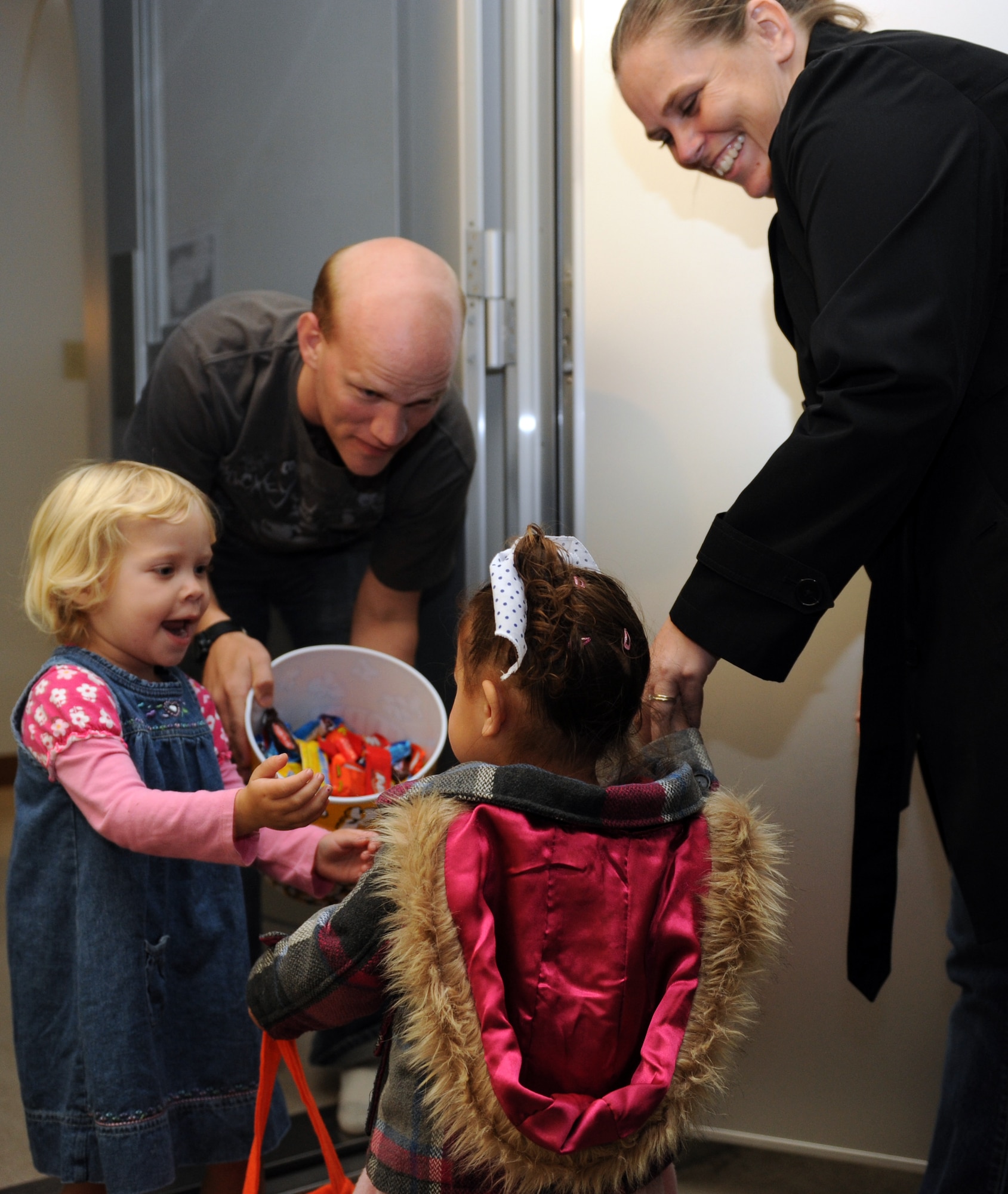 U.S. Air Force Staff Sgt. Stephen Ocenosak, 35th Fighter Wing Public Affairs broadcaster, and his daughter, left, hand out candy to trick-or-treaters on Halloween at Misawa Air Base, Japan, Oct. 31, 2012. Trick-or-treating evolved from the ancient Celtic tradition of putting out treats and food to appease spirits who roamed the streets during a sacred festival called Samhain. (U.S. Air Force photo by Airman 1st Class Kia Atkins)