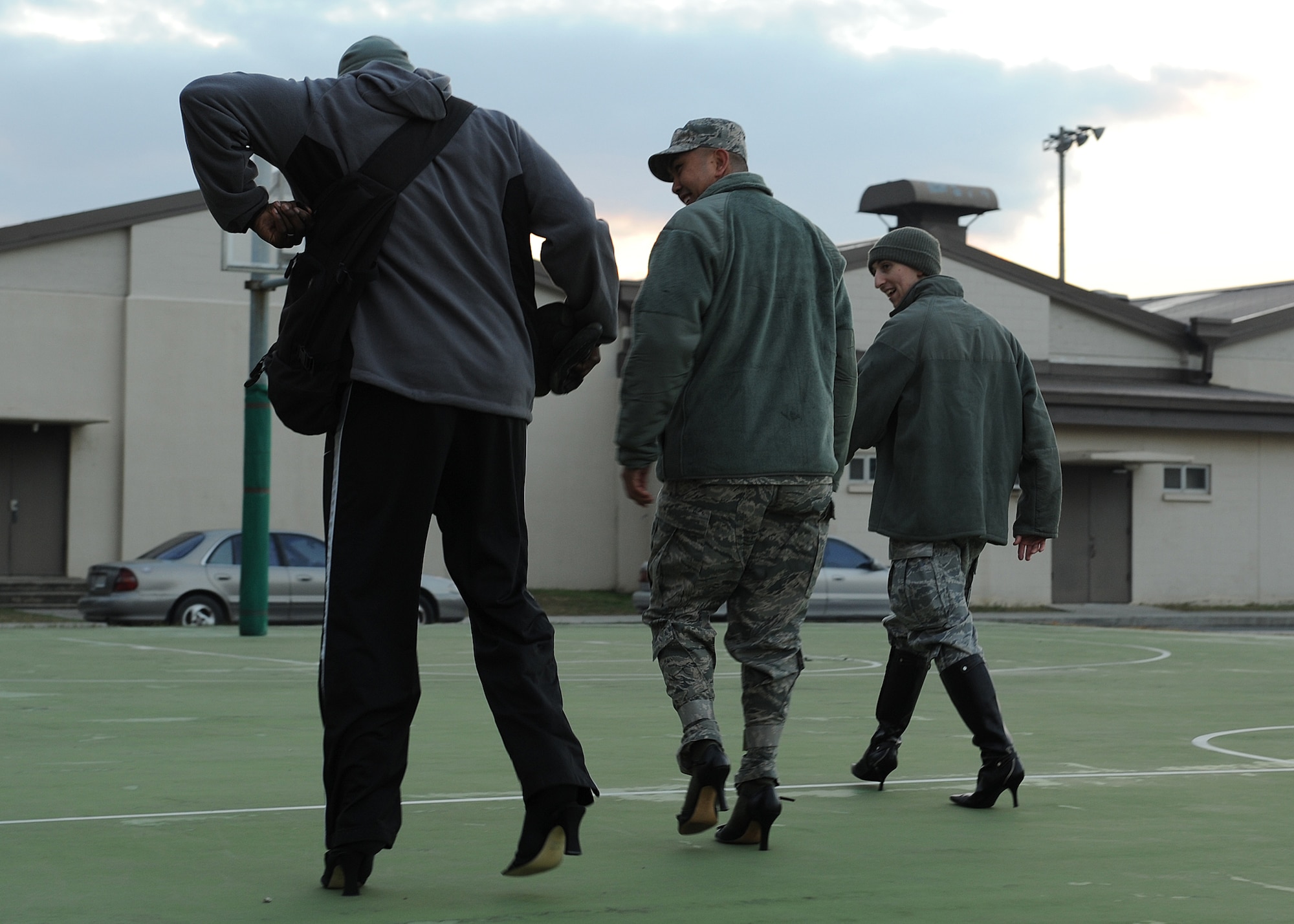 From left: Staff Sgt. Jeremy Smith, Master Sgt. Andrew Toloza, and Staff Sgt. Brent Hicks walk down a basketball court while wearing high heels during the Walk-A-Mile-In-Her-Shoes event on Kunsan Air Base, Republic of Korea, Oct. 31, 2012. The event was an effort to bring awareness to domestic violence and a push to end it. Smith and Toloza are with the 8th Force Support Squadron and Hicks is with the 8th Maintenance Squadron. (U.S. Air Force photo/Staff Sgt. Jonathan Fowler)