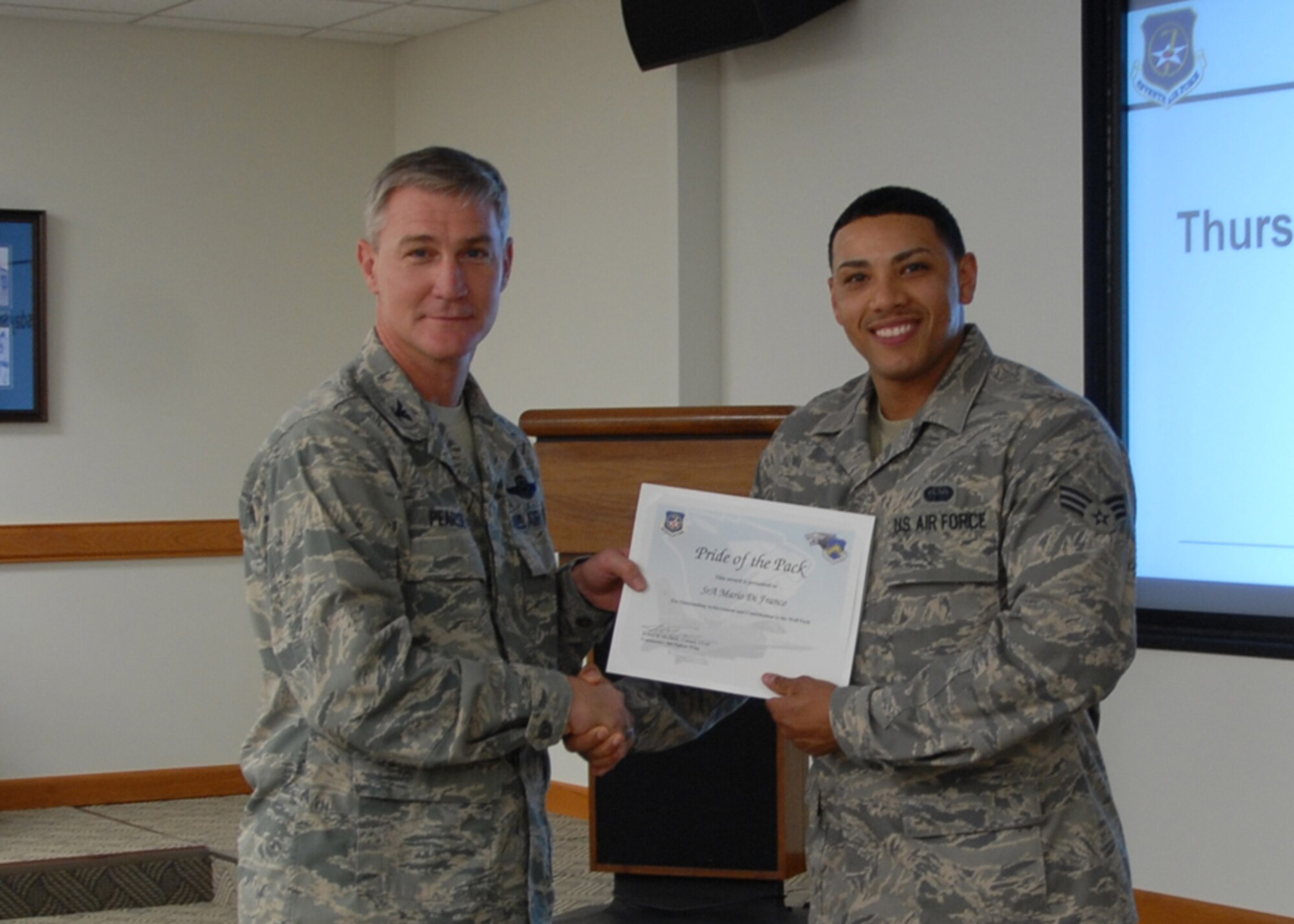 Col. John Pearse, 8th Fighter Wing commander, presents Senior Airman Mario Di Franco, 8th Communications Squadron, with the weekly "Pride of the Pack" award Oct. 25, 2012, at Kunsan Air Base, Republic of Korea. Di Franco was nominated for the award for his accomplishments as a radar technician. (U.S. Air Force photo by Capt. Sheila Johnston)