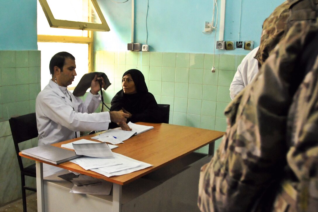 An Afghan doctor, left, provides medical care to an Afghan woman, right, at a key leader engagement with Provincial Reconstruction Team Farah and Afghan doctors, and public health professionals at Farah City Hospital, in Farah City, Afghanistan, Oct. 30, 2012. 