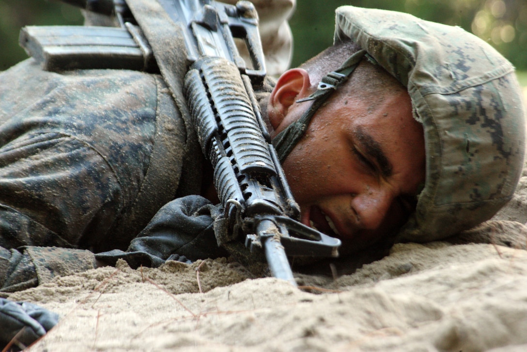 Rct. Sebastian Castro Gomez, an 18-year-old native of San Juan, Puerto Rico, of Platoon 3072, Lima Company, 3rd Recruit Training Battalion, low crawls between obstacles during Basic Warrior Training on Parris Island on Sept. 14, 2012. The recruits pressed their heads into the sand as they advanced to make themselves smaller targets as they maneuvered toward their objective.