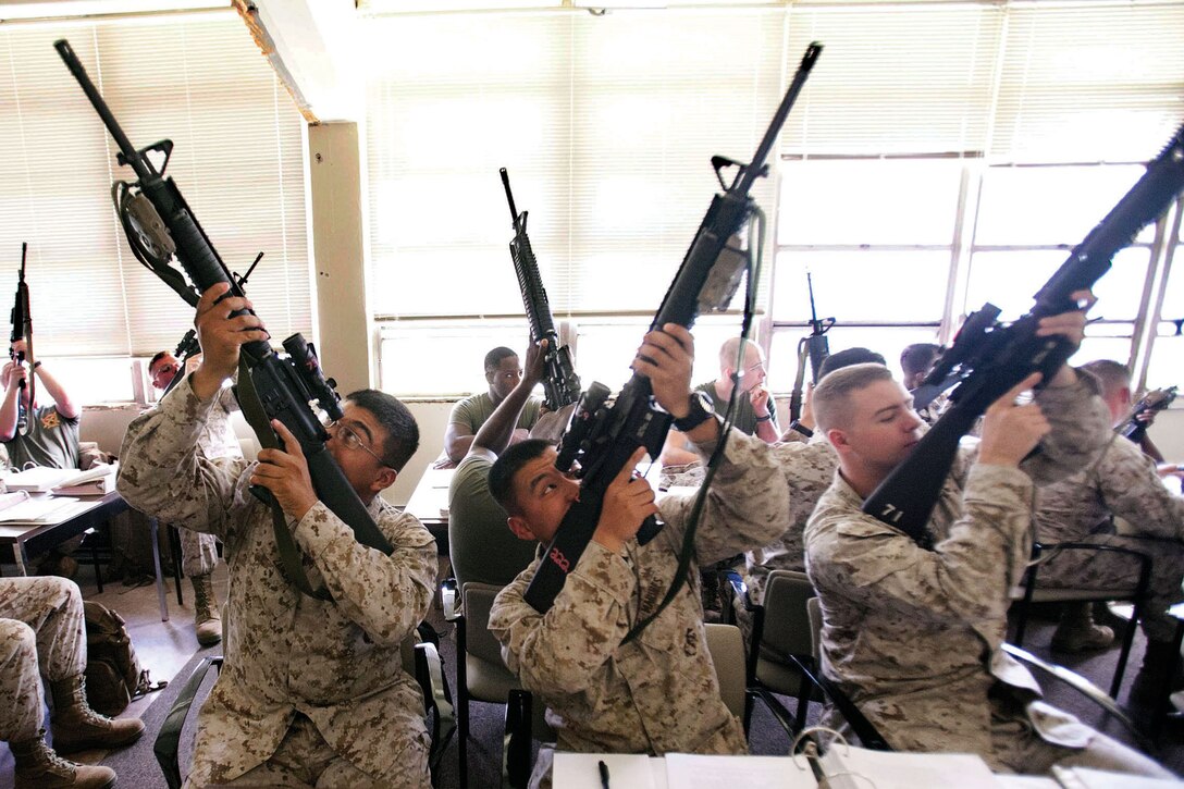 Marines look through their rifle optics during a rifle and pistol coaches course Oct. 26 at Camp Hansen. The course taught the students the fundamentals of the rifle and pistol and gave them the confidence and skills needed to be range coaches. 