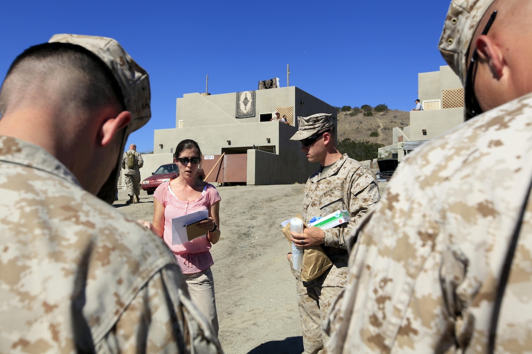 Agent Angel Tommervik (center), with Criminal Investigative Services, briefs  2nd Lt. Kevin Mills (center-right), the 1st platoon commander of Military Police Company, and his team on a mock crime scene scenario during training on the new Three-Dimensional Policing Model here Oct. 15-19. 