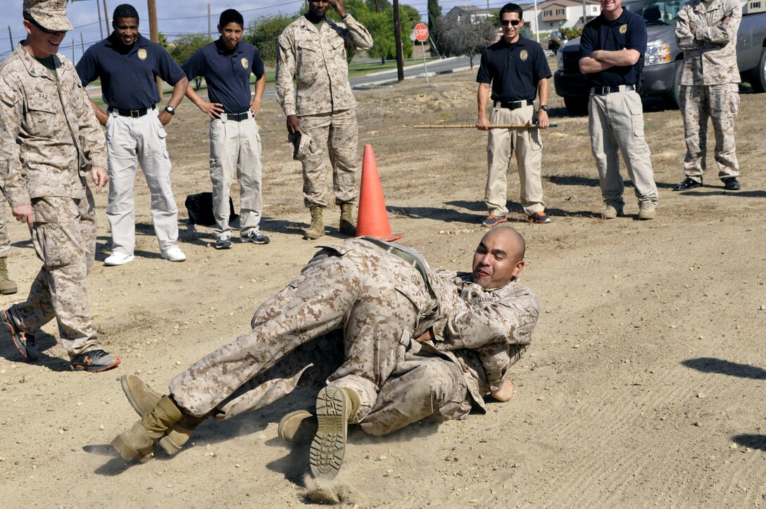 Sgt. Christopher Orozco, from the special reaction team here, and LCpl. Paul Turk, also from the SRT, grapple in a field as a section of the class waits away from the group to later analyze the crime scene during a class designed to hone their tracking skills through a new Three-Dimensional Policing Model here Oct. 15-19.