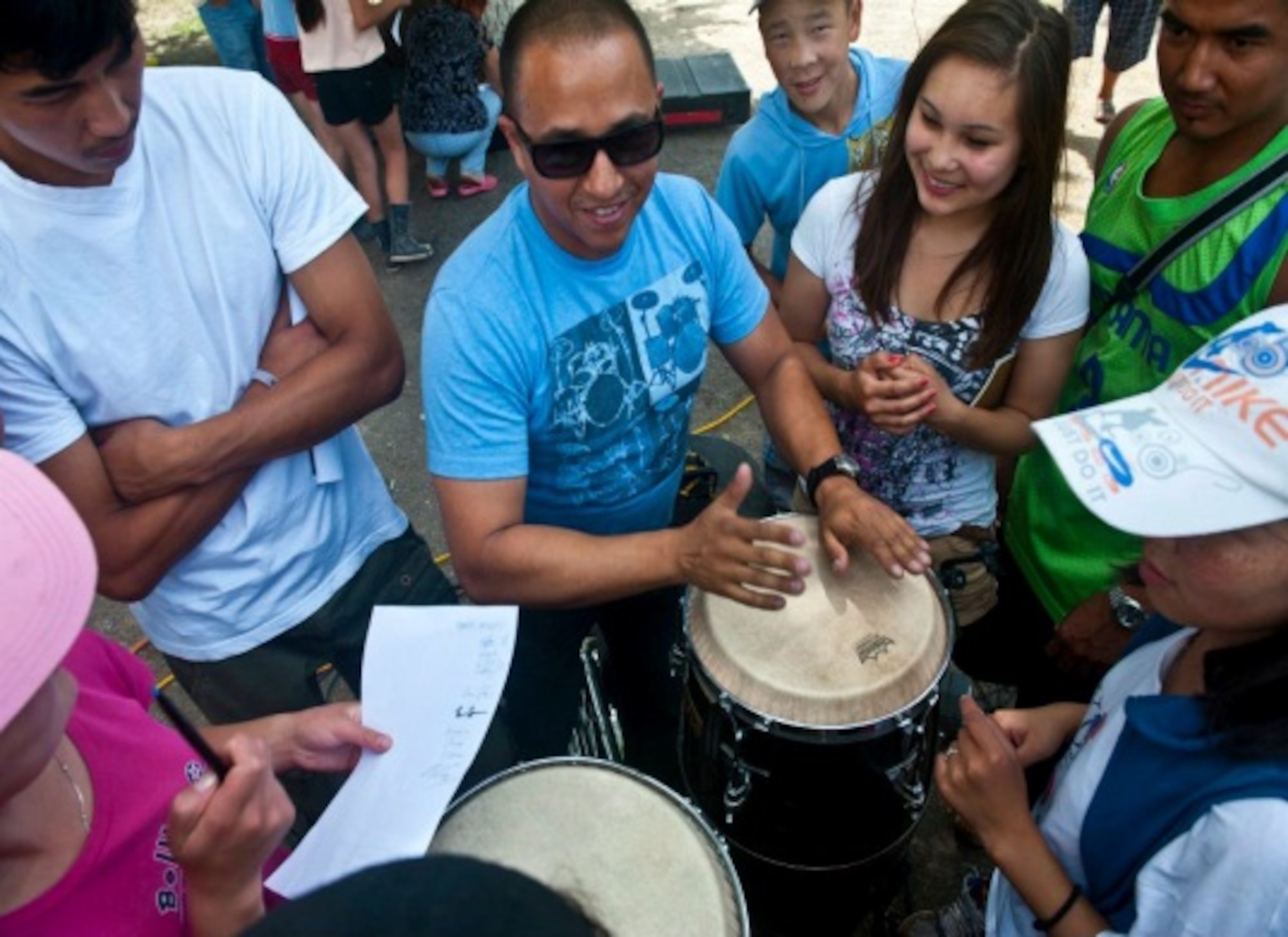 Senior Airman David Rodriguez plays bongos for Kyrgyz Republic children after a U.S. Air Forces Central Band "Vector" performance at the Mayak Camp. Courtesy photo from AFCENT Band. 