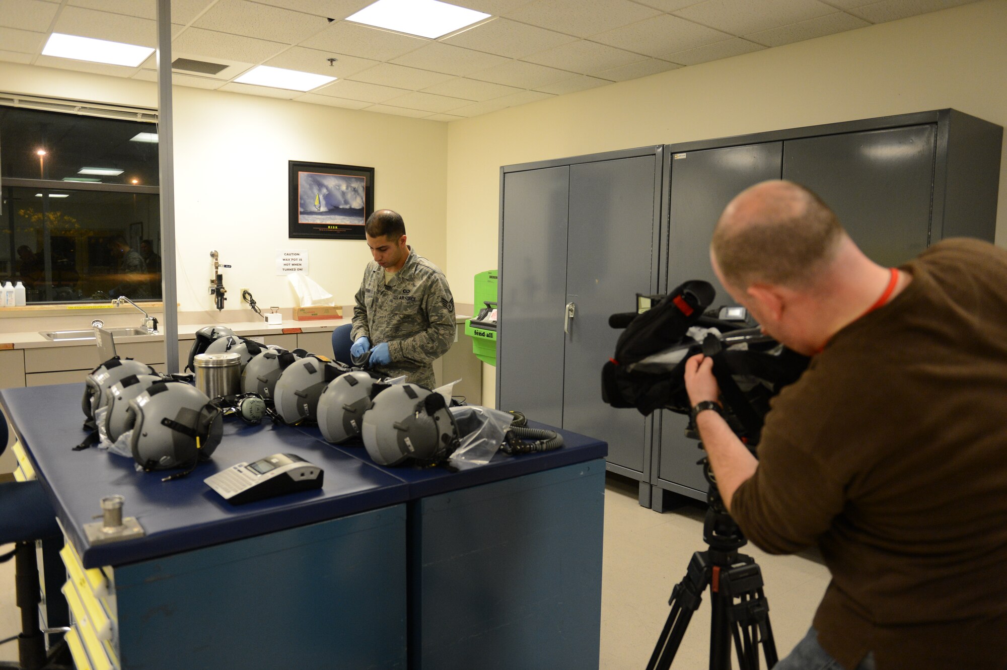 Staff Sgt. Omar Ansari, 62nd Operations Support Squadron aircrew flight equipment journeyman, performs an inspection Nov. 1, 2012, on aircrew protective helmets, as a news crew interviews him, at Joint Base Lewis-McChord, Wash. The news crew, from Seattle's Q13 Fox channel, was on hand to cover McChord Field's involvement in Hurricane Sandy relief efforts. (U.S. Air Force photo/Staff Sgt. Sean Tobin)