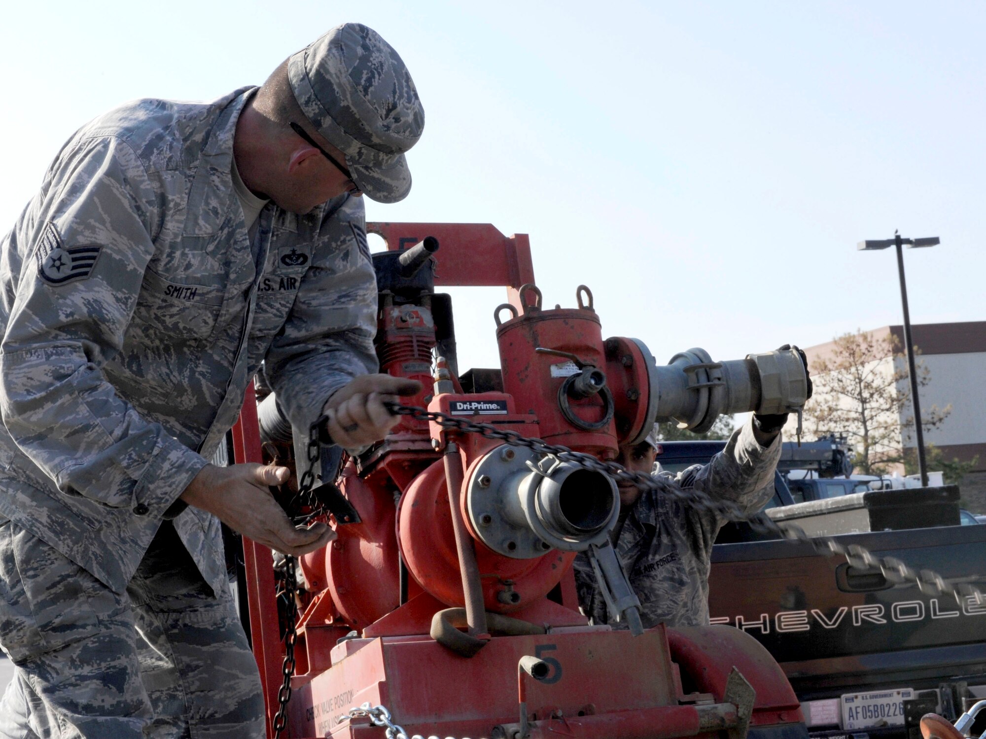 U.S. Air Force Staff Sgt. Michael Smith, left, and Staff Sgt. Alexis Lopez, right, 633rd Civil Engineer Squadron water fuels systems journeymen, chain a water pump onto a trailer prior to transport at Langley Air Force Base, Va., Nov. 2, 2012. The 633rd CES team transported the equipment in support of Hurricane Sandy disaster relief in New York. (U.S. Air Force photo by Staff Sgt. Krystie Martinez/Released)