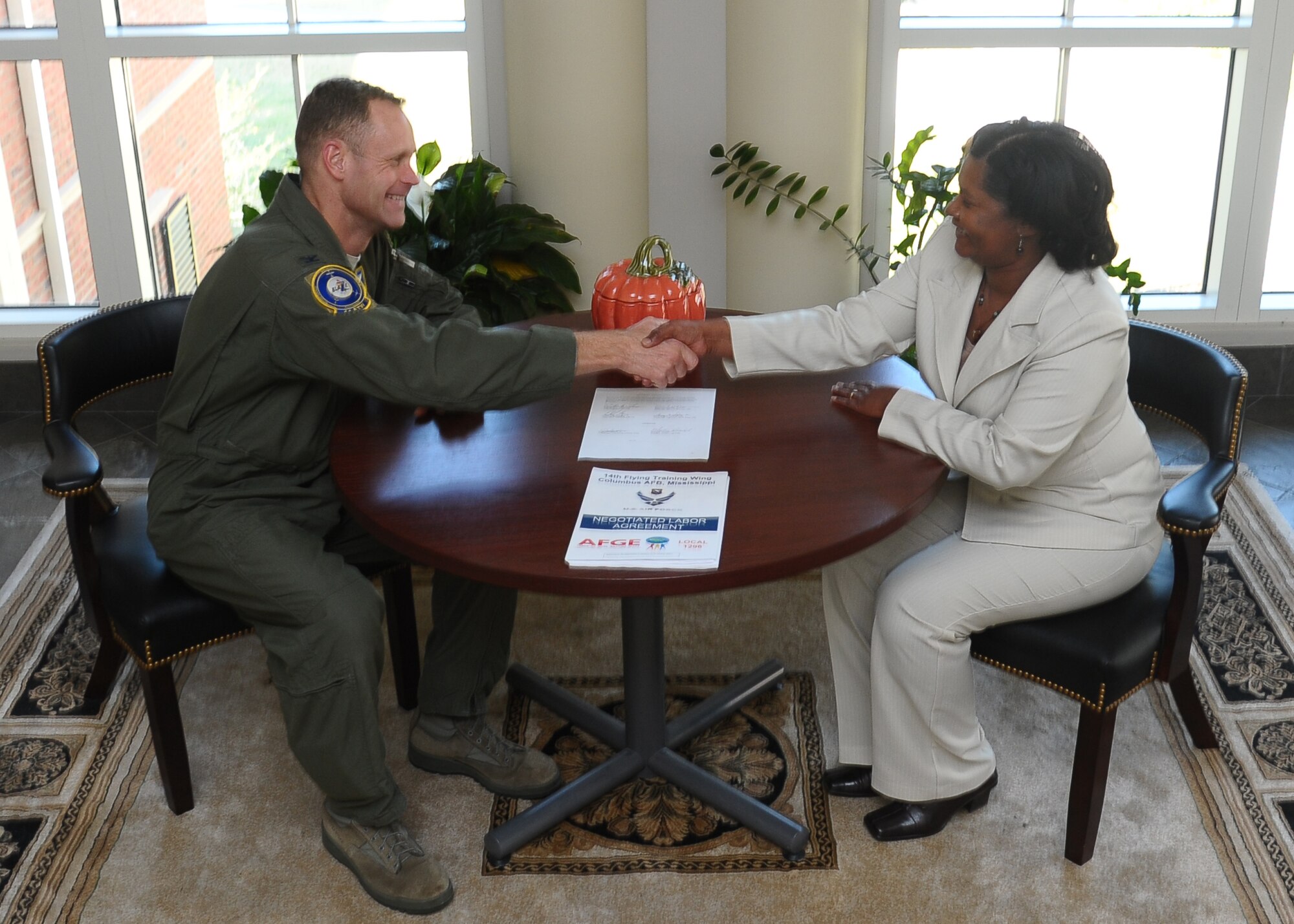 14th Flying Training Wing Commander Col. Jim Sears, and Mattie Head, American Federation of Government Employees Local 1296 president shake hands over the newly signed Collective Bargain Agreement. The CBA is an agreement between the union and the 14th FTW defining issues that impact the government work force working conditions here at Columbus Air Force Base. (U.S. Air Force photo/Senior Airman Chase Hedrick)