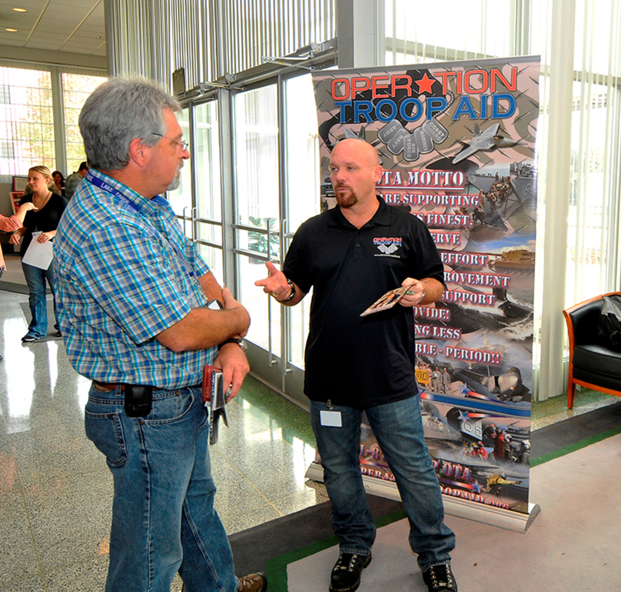 From left, AEDC Contracting Officer Robert Greene listens to Mark Woods explain the mission of the organization he represents, Operation Troop Aid, during the recent CFC fair held on base. Wood said the organization's goal is to provide care packages to deployed troops. (Photo by Jacqueline Cowan)