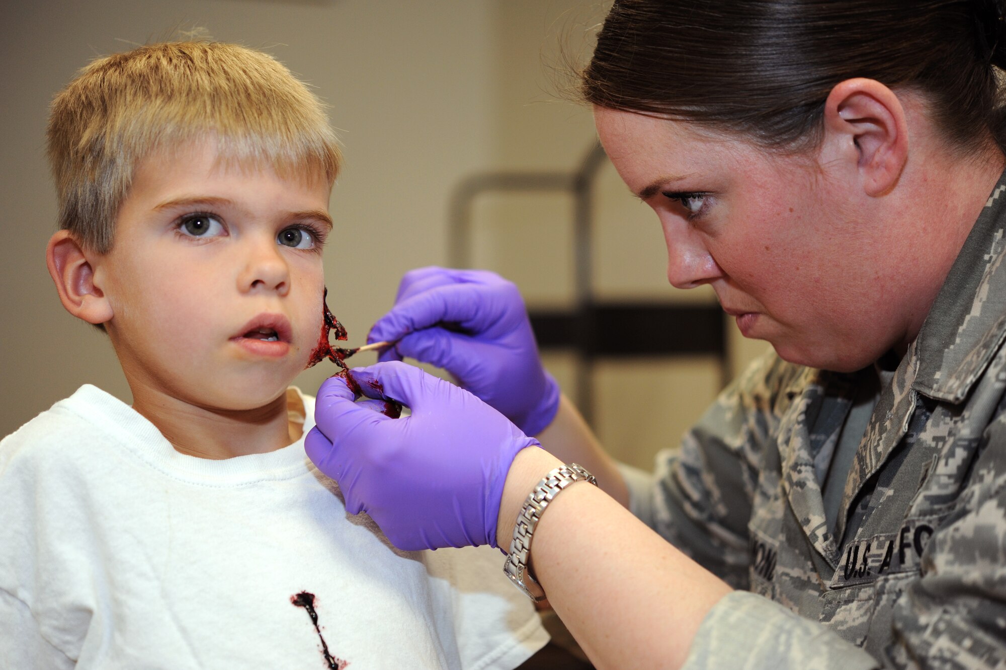 Caleb Clegg, 7, son of Master Sgt. Wade Clegg, is transformed into a zombie for the Zombie Fun Run 5K held Oct. 30 at Vance Air Force Base, Okla. Applying the moulage makeup to Caleb is Staff Sgt. Amanda Lenamond, 71st Medical Operations Squadron. (U.S. Air Force photo/ Staff Sgt. James Bolinger)