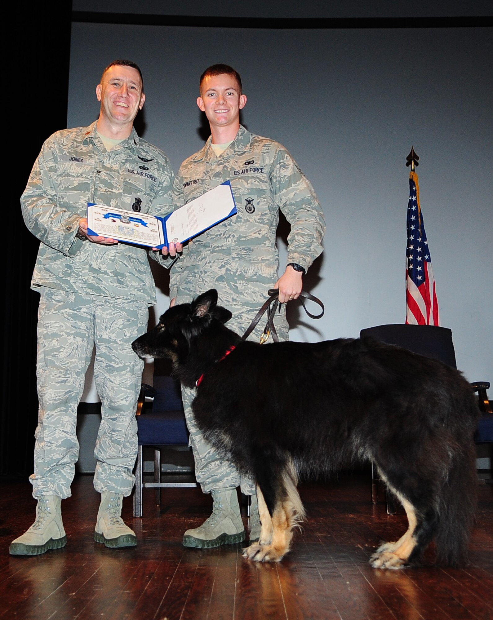 U.S. Air Force Maj. Troy Jones, 4th Security Forces Squadron commander, presents a certificate to Staff Sgt. Joseph Swartout, 4th SFS military working dog handler, and Frisco, retired MWD, during a retirement ceremony on Seymour Johnson Air Force Base, N.C., Oct. 26, 2012. Each of the dogs’ leashes was ceremoniously passed to their new owner prior to receiving their certificate. (U.S. Air Force photo/Airman 1st Class Aubrey White/Released)