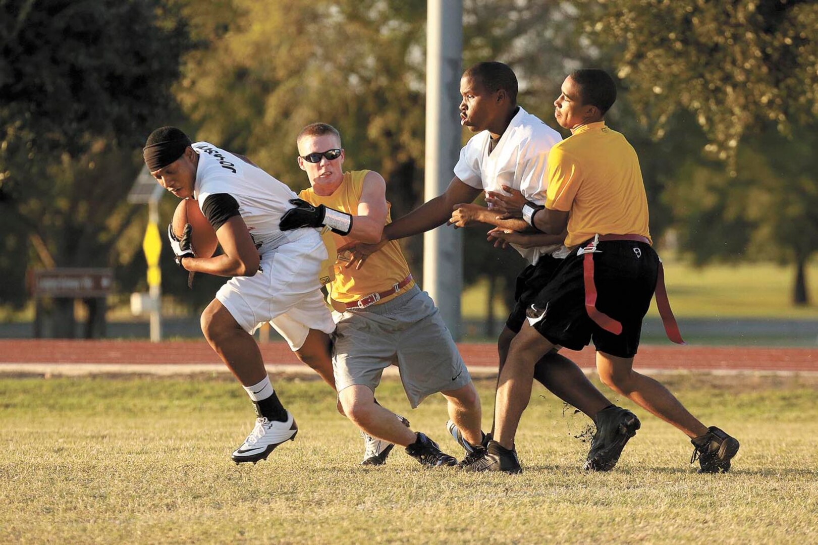 59th Dental Group wide receiver Aaron Johnson attempts to break away from 688th Information Operations Wing defenders with assistance from teammate Michael Smith. (U.S. Air Force photo/Robbin Cresswell)