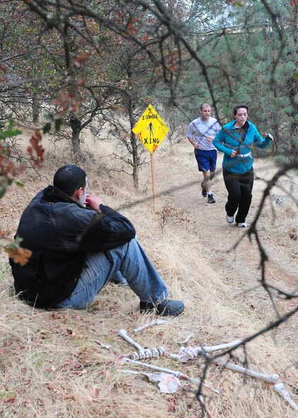 A zombie leers hungrily at Team Beale members as they continue along the path of the 2nd annual Zombie Run at Beale Air Force Base Calif., Oct. 31, 2012. More than 100 runners and volunteer zombies competed in the run. (U.S. Air Force photo by Senior Airman Allen Pollard/Released)