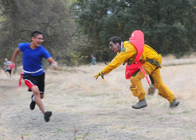A Team Beale member eludes a zombie during the 2nd annual Zombie Run at Beale Air Force Base Calif., Oct. 31, 2012. Zombie volunteers hid throughout the course, scaring and chasing runners in attempts to capture their flags. (U.S. Air Force photo by Senior Airman Allen Pollard/Released)