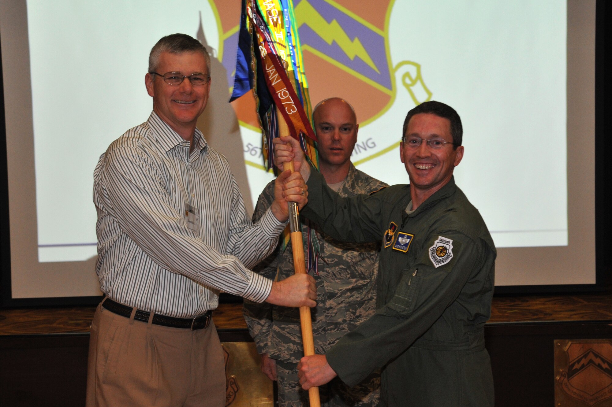 Brig. Gen. Mike Rothstein, 56th Fighter Wing commander, hands the guidon to Tom Harris, 56th Fighter Wing honorary commander, and Arizona Diamondbacks executive vice president and chief financial officer, Oct. 26 during the Honorary Commanders Ceremony held at Club Five Six. (U.S. Air Force photo by Senior Airman Sandra Welch)