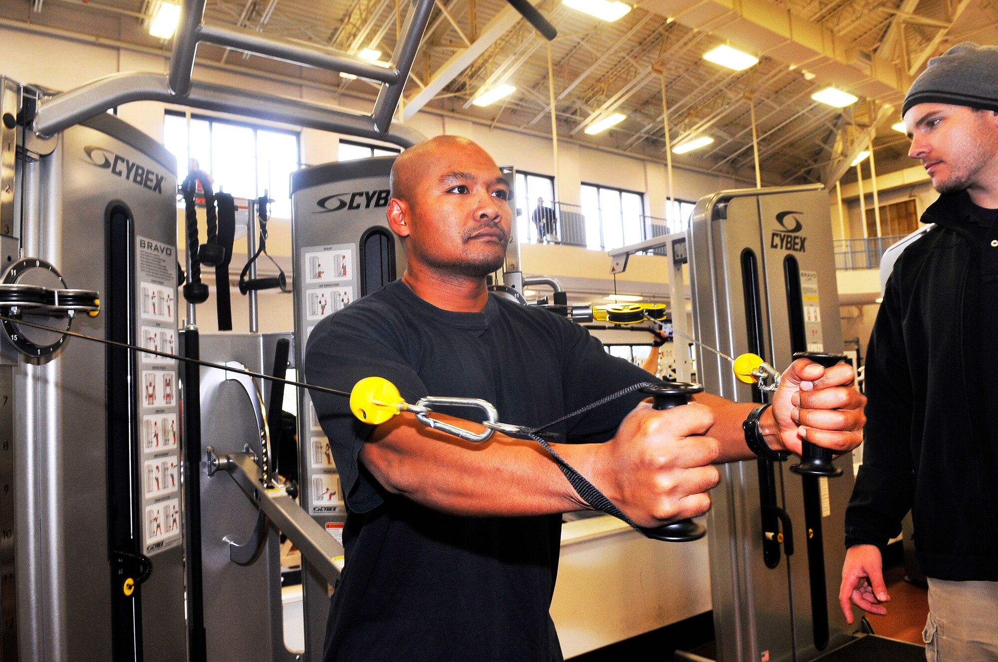 Adam McDonald, at right, Fitness Center recreation assistant, assists David Yann with a workout on one of the new Bravo line functional trainers. (U. S. Air Force photo/Sue Sapp)