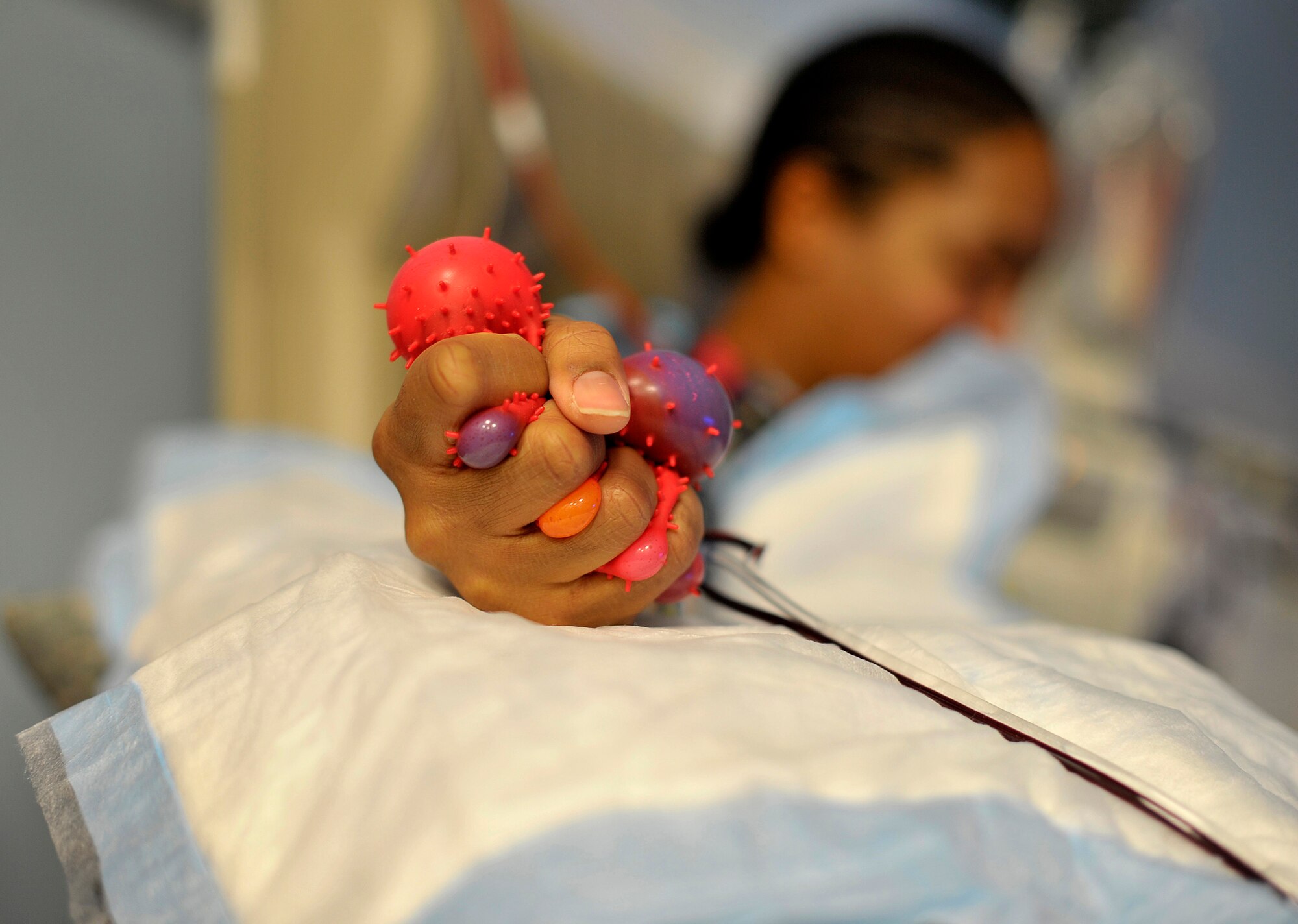U.S. Navy Hospitalman 2nd Class Ashley Tapia squeezes a ball to help flood flow in her arm while she donates platelets at the apheresis section of the NATO Role 3 Hospital at Kandahar Airfield, Afghanistan, Oct. 25, 2012. The apheresis section is managed by a U.S. Air Force five-member team that collects platelets from repeat donors, which in turn is used to help trauma patients at the Role 3 hospital and 14 Forward Operating Bases throughout Afghanistan. (U.S. Air Force photo/Staff Sgt. Clay Lancaster)