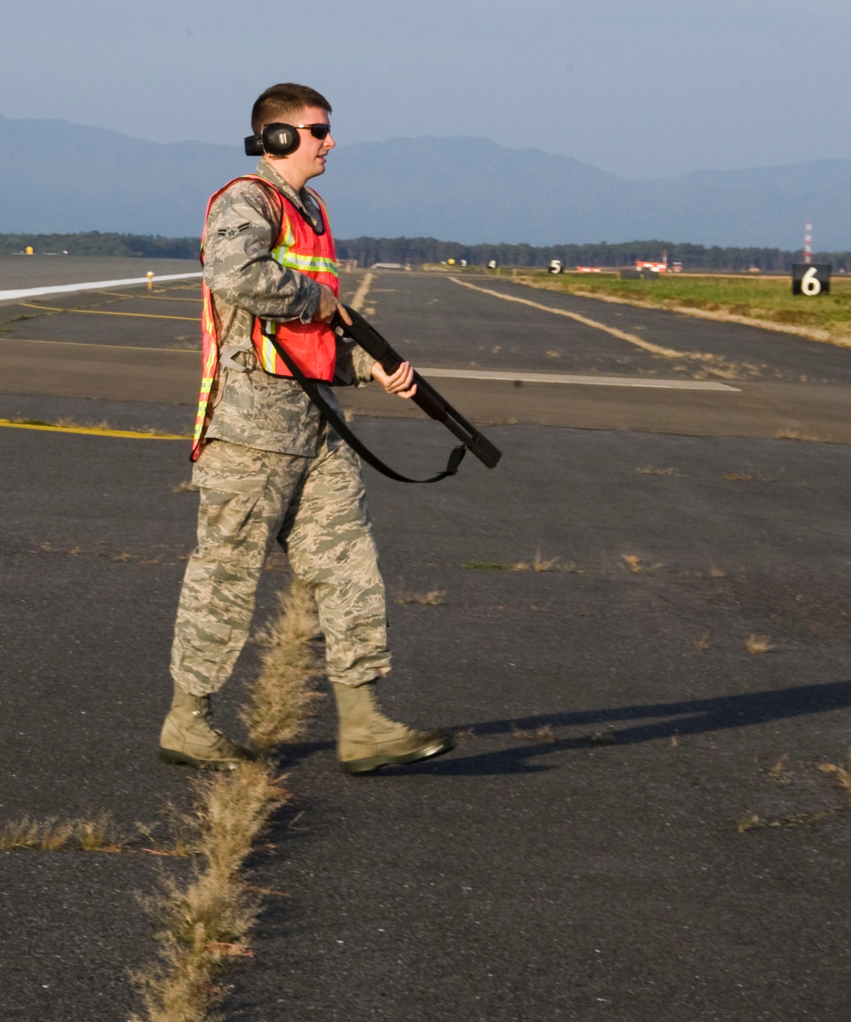 U.S. Air Force Airman 1st Class Jarrett Dowey, 35th Operations Support Squadron airfield management operations coordinator, walks across the flightline taxi-way in preparation to scare birds at Misawa Air Base, Japan, Oct. 30, 2012. Airfield management drives around the flightline three times a day to perform bird aircraft strike hazard prevention. (U.S. Air Force photo by Airman 1st Class Kenna Jackson)