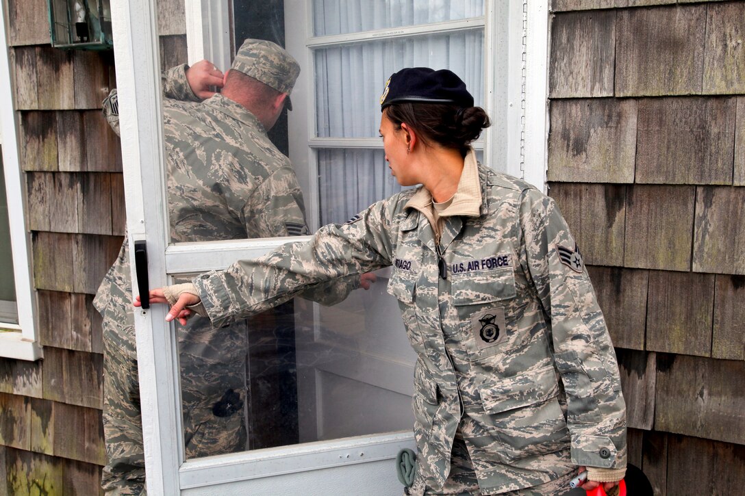 Air Force Senior Airman Stardust S. Santiago holds the door open for Staff Sgt. Ryan A. Osmola as they check a home to ensure no one inside is in distress on Long Beach Island, N.J., Nov. 1, 2012. Santiago and Osmola are assigned to the 177th Fighter Wing, New Jersey Air National Guard, which is working with civil authorities in an effort to assist residents affected by Hurricane Sandy. 