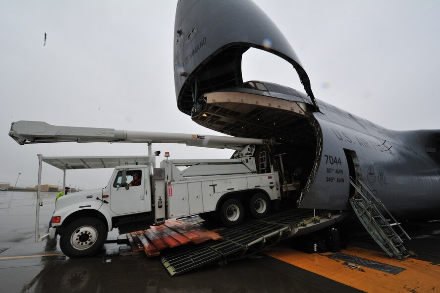 A BPA utility vehicle weighing about 50,000 pounds and stretching about 35 feet is slowly backed into the mouth of at Travis Air Force Base C-5 Galaxy on the flightline at Fairchild AFB, Wash., Nov. 3. The wooden ramp allows the vehicles to enter without the top scraping against the roof of the aircraft. The C-5 departed with 19 BPA employee volunteers and five of their 14 vehicles at about 11 a.m. for Joint Base McGuire Dix Lakehurst. The rest of the vehicles are being flown to the East Coast by two C-17 Globemasters assigned to Joint Base Charleston, S.C. BPA will make their way to Long Island, New York to help restore power that was knocked out by Hurricane Sandy. (U.S. Air Force photo by Airman 1st Class Taylor Curry)