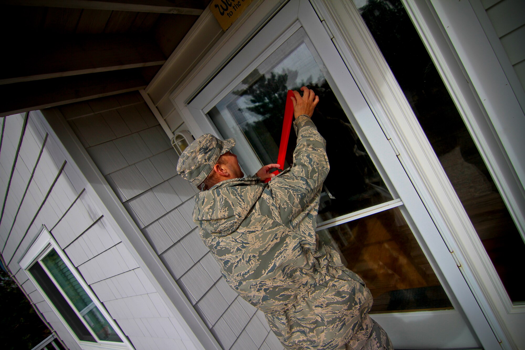 A picture of an Airmen from the 177th Fighter Wing placing red tape over a glass door.