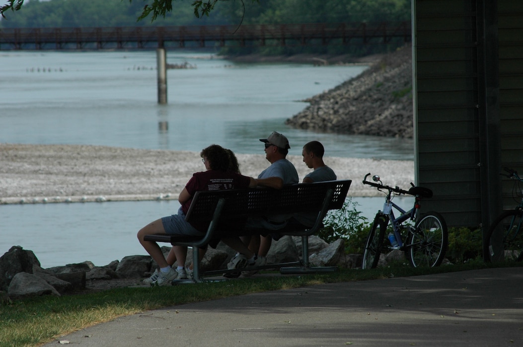 Family sitting on bench watching river in South Tailwater
