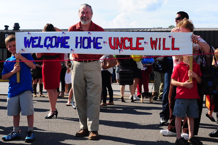 Sam and Benjamin McDougall hold up a sign while waiting for the return of the 17th Airlift Squadron to welcome home their uncle, Maj. William McDougall, 17th AS pilot, Nov. 4, 2012, at Joint Base Charleston - Air Base, S.C. While deployed, the 17th AS executed 143 airdrops which resupplied service members serving in the regions with 5.7 million pounds of supplies. (U.S. Air Force photo/ Airman 1st Class Chacarra Walker)