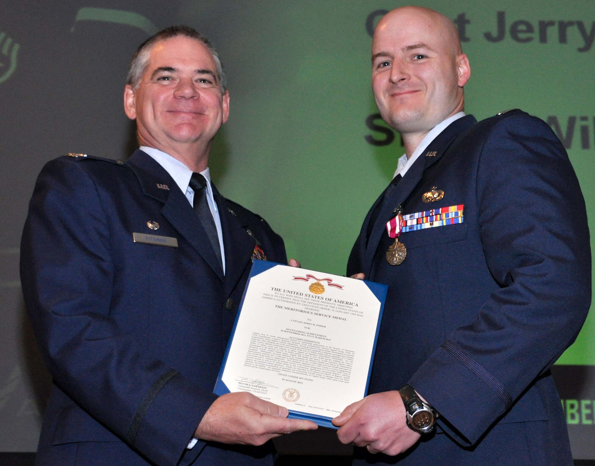 Air Force Reserve Col. Jay Pittman, 302nd Airlift Wing commander, presents the Air Force Meritorious Service Medal to Capt. Jerry Snider Nov. 4 during a wing commander's call at Peterson Air Force Base, Colo. Snider, assigned to the 302nd Logistics Readiness Squadron, earned the medal for actions performed while deployed to Afghanistan. (U.S. Air Force photo/Staff Sgt. Stephen J. Collier)