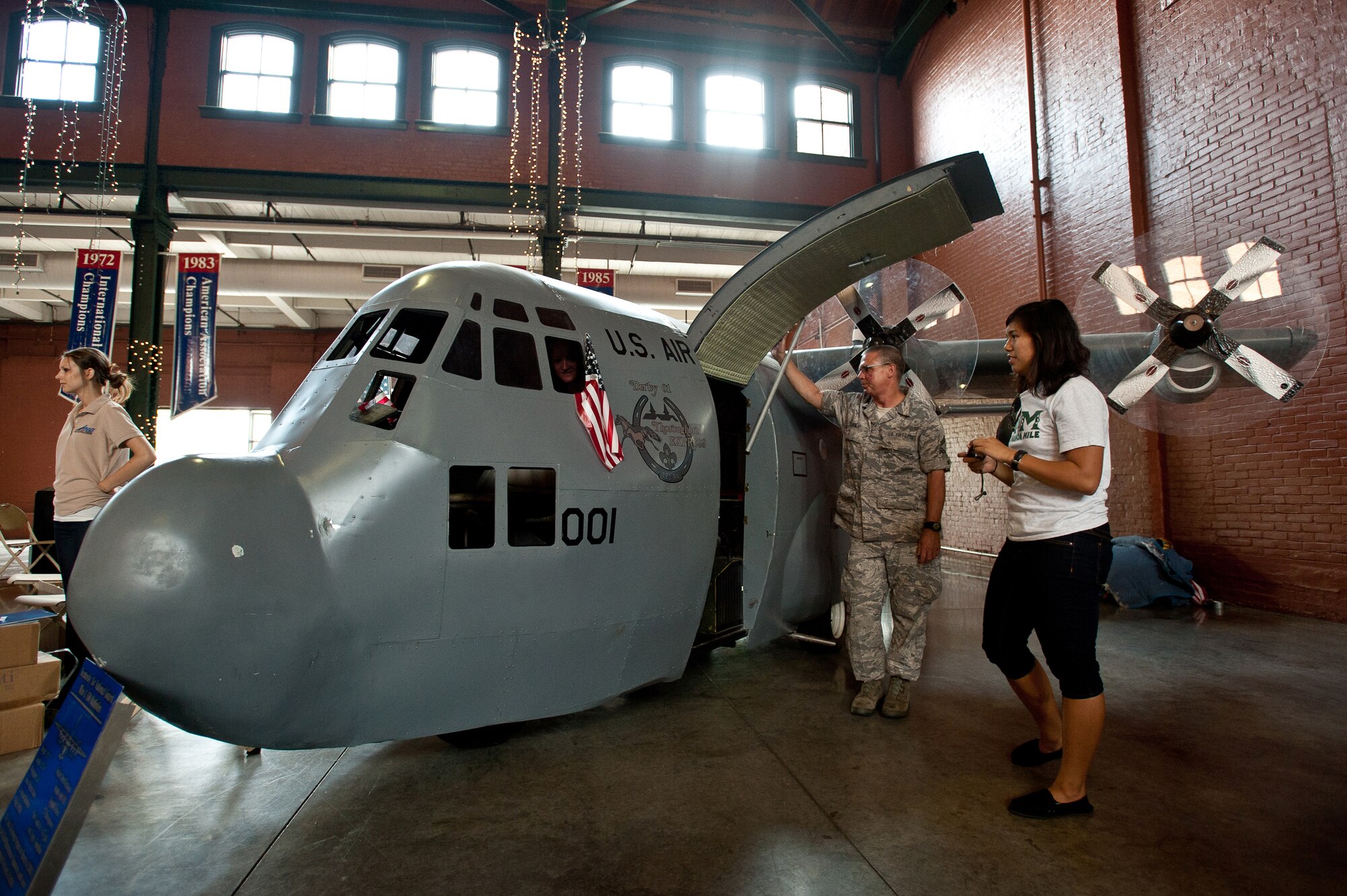 Senior Master Sgt. Gary Dunlap, NCOIC of the propulsion flight in the Kentucky Air National Guard???s 123rd Maintenance Squadron, shows off the unit???s Mini C-130 to baseball fans during the Louisville Bats-Syracuse Chiefs game May 28, 2012, at Slugger Field in Louisville, Ky. The Mini C-130 is a scale replica of its airborne big sister, the C-130 Hercules cargo aircraft flown by the men and women of the Louisville-based 123rd Airlift Wing.Although incapable of flight, the Mini C-130???s realistic sheet-metal and steel-frame construction features working propellers, a functional cargo door, UHF radio, high-powered stereo system and seating for up to a dozen passengers. The replica was built from scratch by the Airmen of the 123rd Maintenance Squadron, using the chassis of a three-wheeled Cushman utility cart as its foundation. It is powered by a 27-horsepower gasoline motor and can reach speeds of up to 20 mph. The replica is a big hit with children, who???ve eagerly lined up to take ???test flights??? during its many appearances at civic functions across Kentucky and Southern Indiana. The Mini C-130 made its public debut during the 2004 Kentucky Derby Festival parade, where it took top honors in the Specialty Unit category. (U.S. Air Force photo by Maj. Dale Greer)