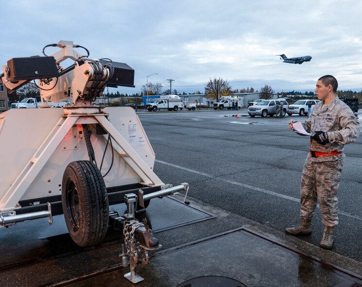 Airman 1st Class Joseph Flores-Constancio, 62nd Aerial Port Squadron cargo processing journeyman, weighs a portable light cart belonging to Bonneville Power Administration, Nov. 3, 2012, as a C-17 Globemaster III aircraft flies overhead, at Joint Base Lewis-McChord, Wash. Before being transported on an aircraft, cargo must be weighed and measured to ensure the aircraft is balanced in flight. (U.S. Air Force photo/Staff Sgt. Sean Tobin)