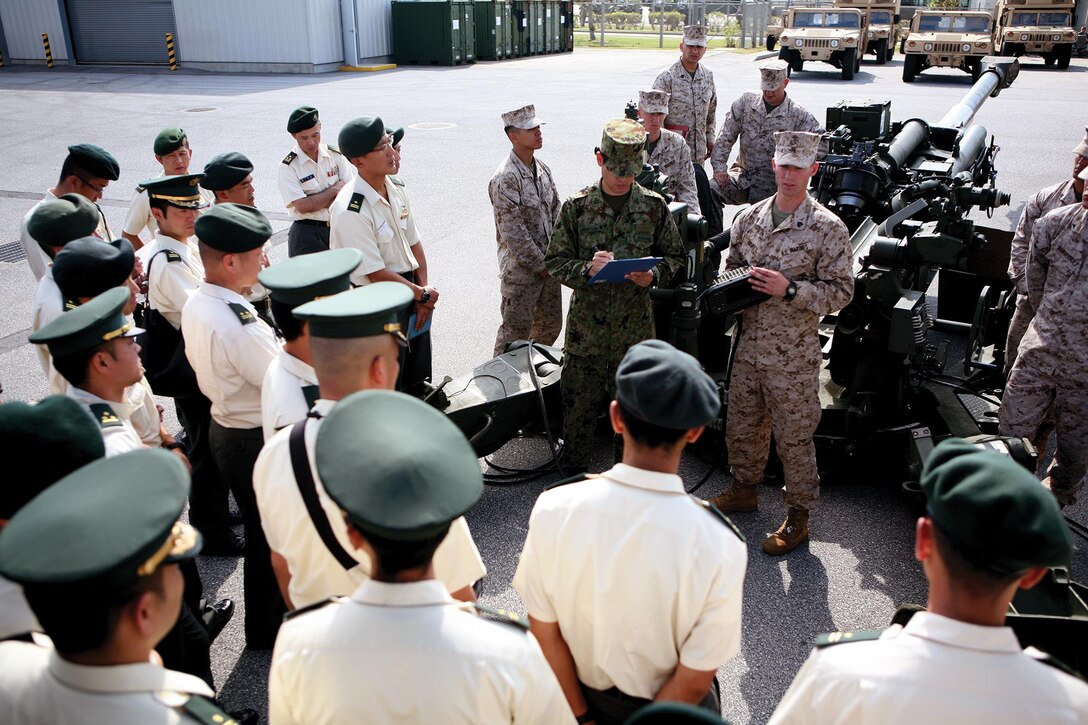 Sgt. Mark A. Dickey briefs the capabilities of the M777A2 155 mm howitzer to Japan Ground Self-Defense Force student-officers during a static display at Camp Hansen Oct. 24. Dickey is a field artillery cannoneer with 3rd Battalion, 12th Marine Regiment, 3rd Marine Division, III Marine Expeditionary Force. The JGSDF student-officers are with Fuji Schools.