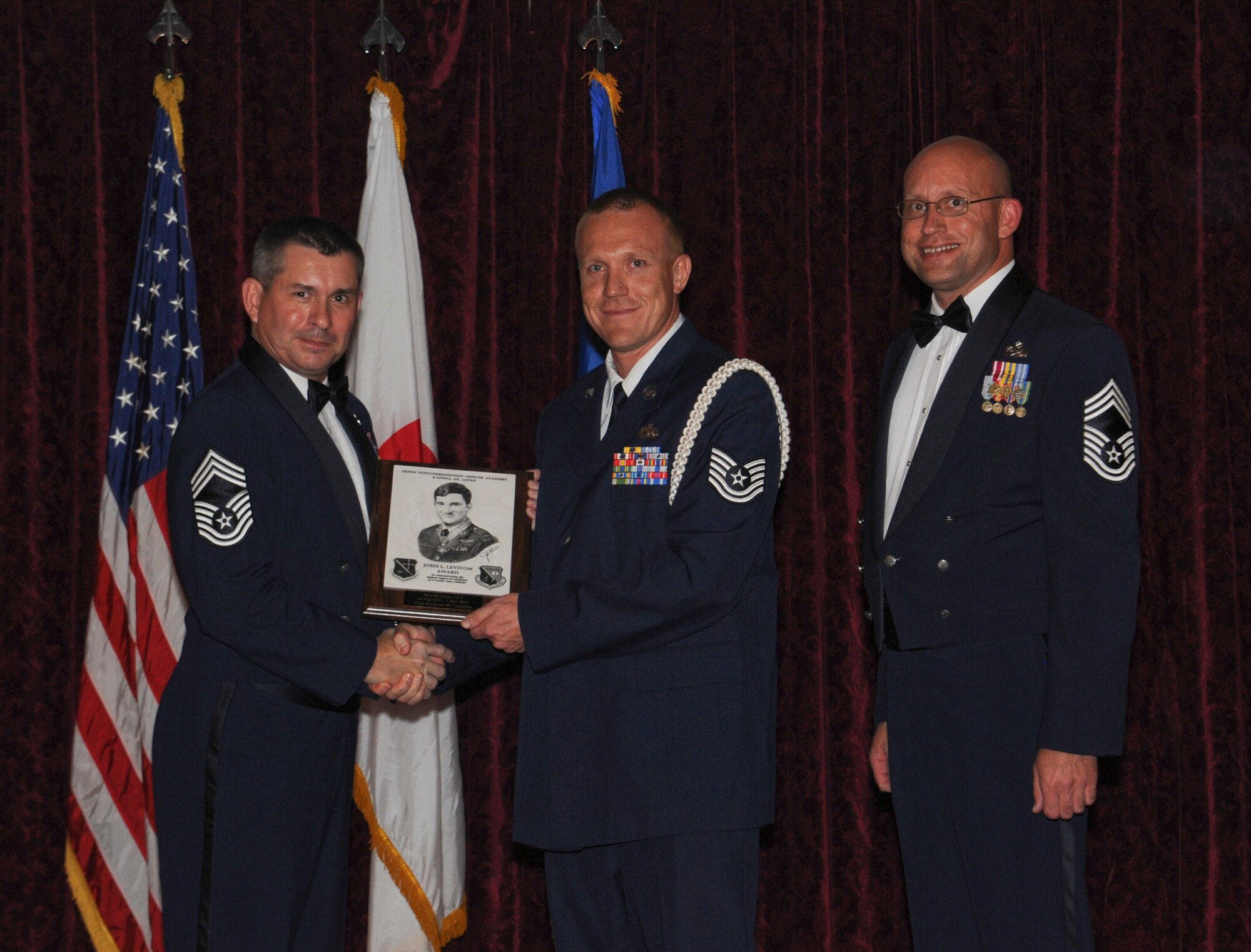 U.S. Air Force Chief Master Sgt. Robert Polomsky, 82nd Reconnaissance Squadron, and Chief Master Sgt. Daniel Beumer, 961st Maintenance Unit superintendent, present the John L. Levitow Honor Graduate award to Tech Sgt. Richard W. Crossley, 36th Maintenance Squadron, at the NCO Academy graduation ceremony at the Rocker NCO Club on Kadena Air Base, Japan, Nov. 1, 2012. This distinguished graduate award, sponsored by the Kadena Chiefs group, is named in memory of Medal of Honor recipient, Airman 1st Class John L. Levitow. The award is presented to the most outstanding member of class 12-7 and denotes superior achievement as both a leader and a scholar. (U.S Air Force photo/Airman 1st Class Malia Jenkins)