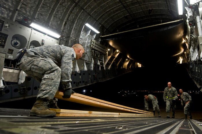 Airmen from the 99th Logistics Readiness Squadron take lumber off of a C-17 Globemaster III out of Travis Air Force Base, Calif., before loading the aircraft with vehicles and personnel from NV Energy Nov. 5, 2012, at Nellis Air Force Base, Nev. The Airmen from the 99th LRS weighed and inspected each vehicle prior to loading. (U.S. Air Force photo by Senior Airman Daniel Hughes)