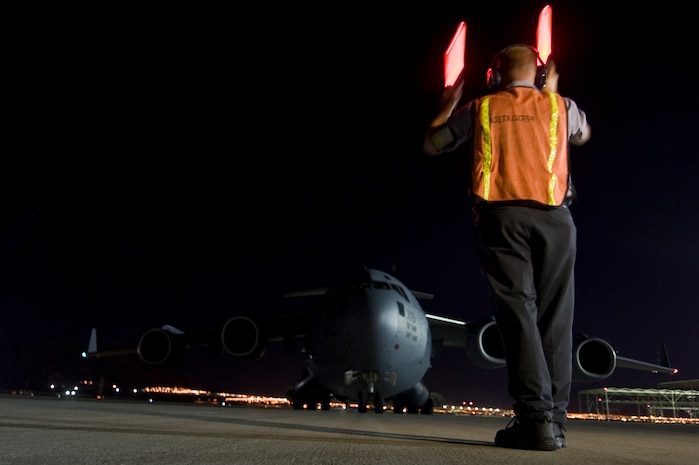 Robert Martz, South Central E&M Co. transit alert, marshals a C-17 Globemaster III from Travis Air Force Base, Calif., Nov. 5, 2012, at Nellis Air Force Base, Nev. The C-17 will carry vehicles and personnel from NV Energy to John F. Kennedy International Airport, N.Y. for Hurricane Sandy relief efforts. (U.S. Air Force photo by Senior Airman Daniel Hughes)