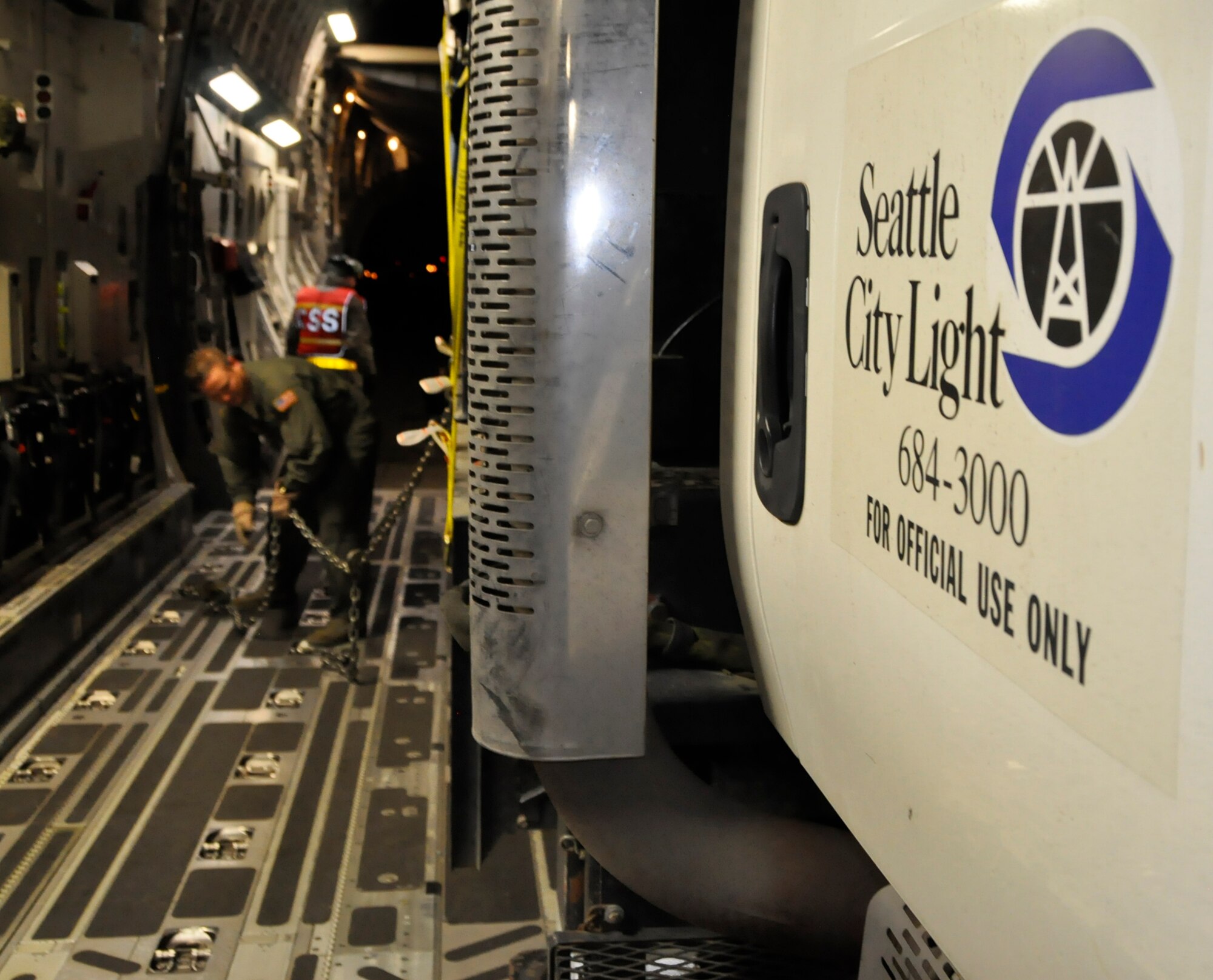 Tech. Sgt. Tom Emmert, a loadmaster from McChord Field's 446th Airlift Wing, unchains a truck from Seattle City Light at John F. Kennedy International Airport in Jamaica, N.Y., Nov. 4. The crew of five Resesrvists loaded and flew 55,000 pounds of cargo and 9 power crew members to help with Hurricane Sandy relief efforts. (U.S. Air Force Photo/Staff Sgt. Rachael Garneau)